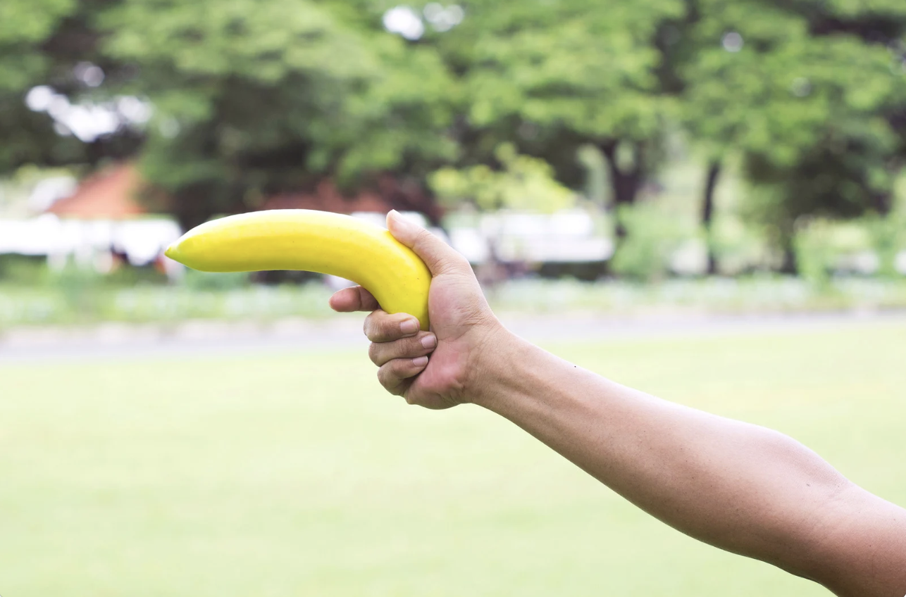 A person holding a banana in the fashion of a gun