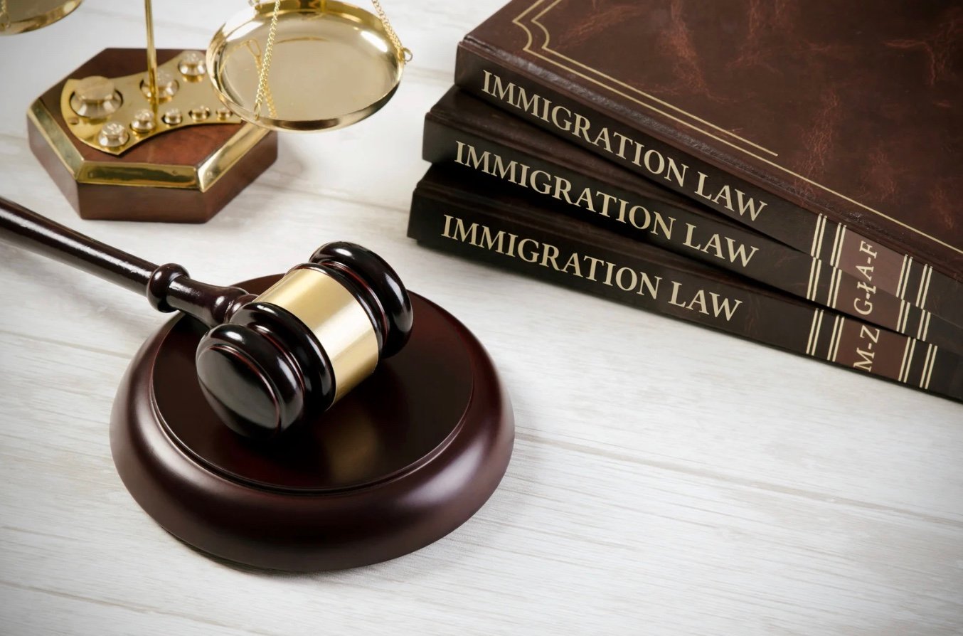 a judges gavel next to three immigration law books, stacked on top of each other