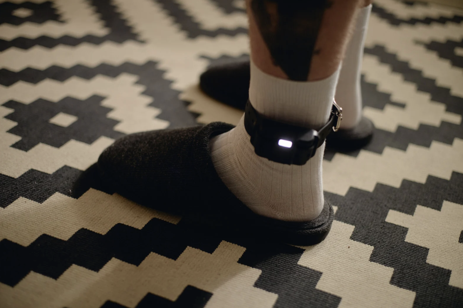 Person at home wearing an ankle monitor 