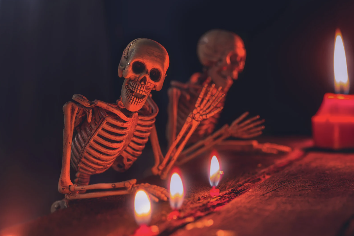 skeletons propped by a candle lit table