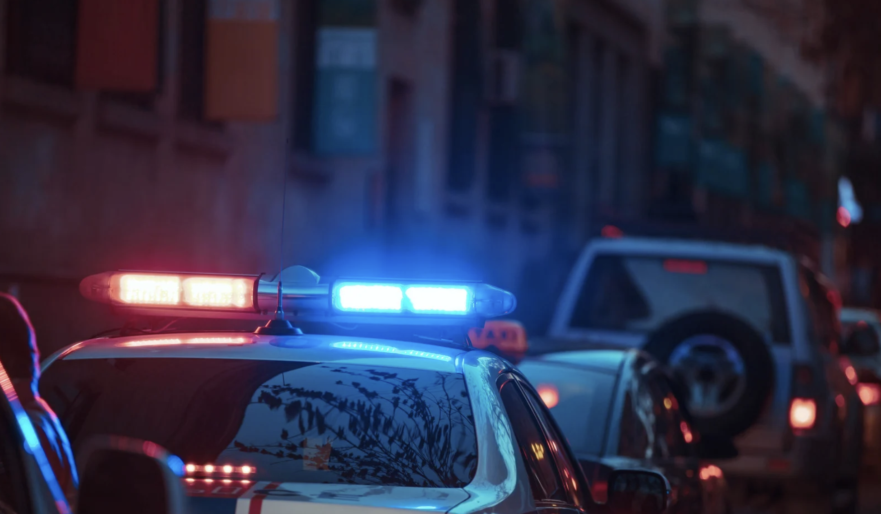 a police car parked on the side of the street at night with it's emergency lights turned on.