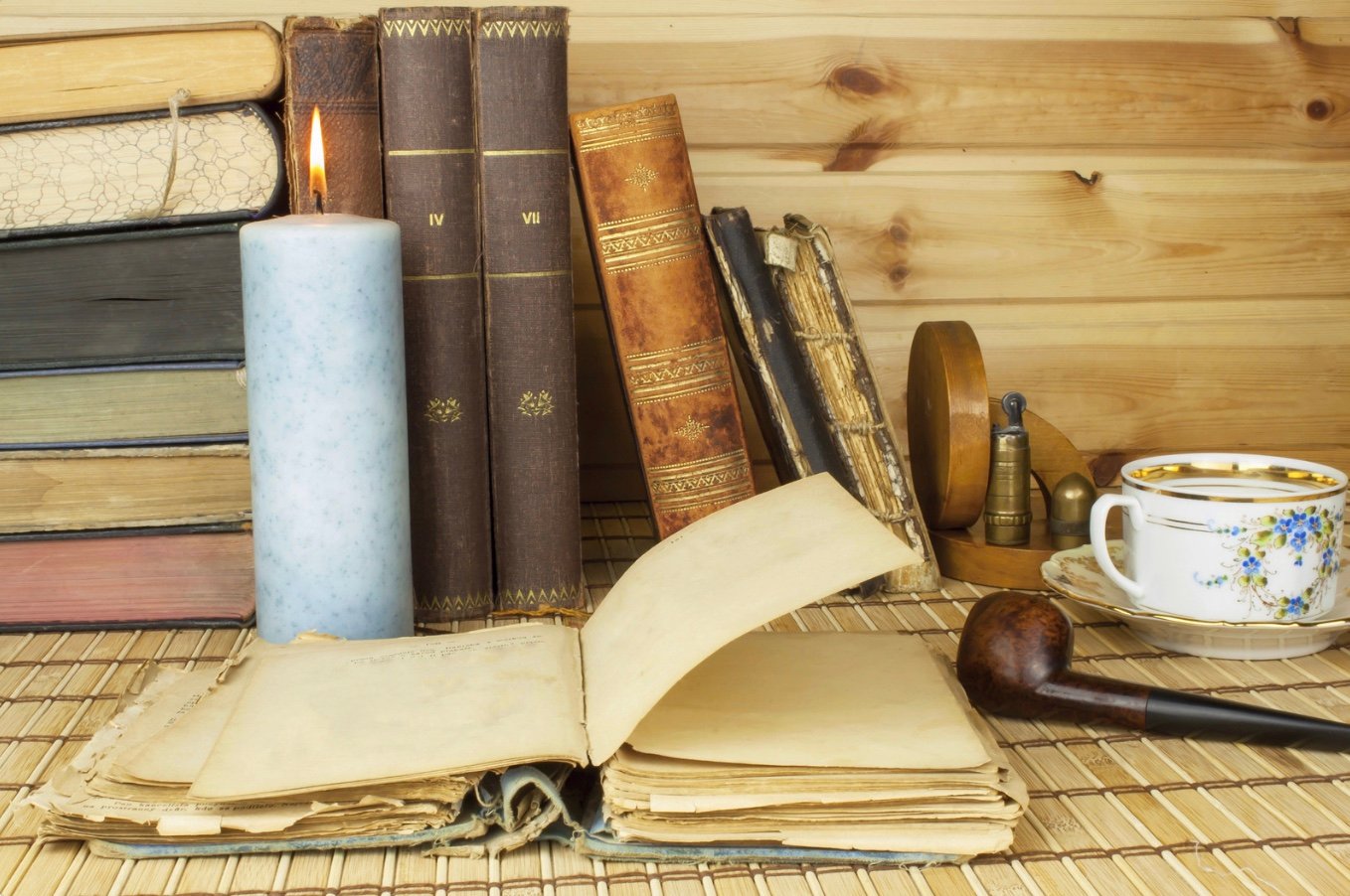 old books by a candle and a smoking pipe