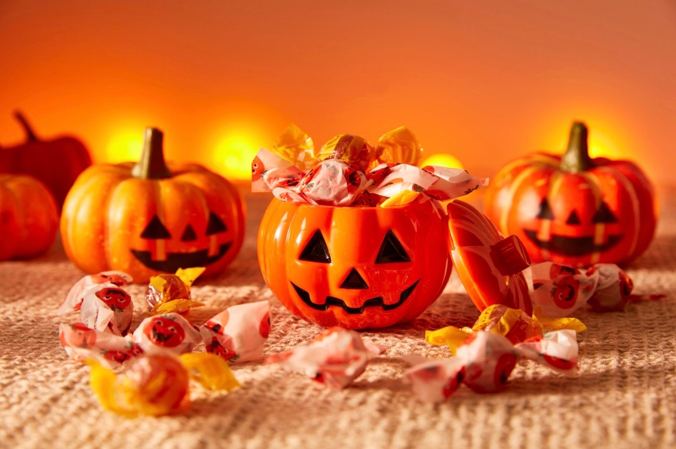 bowls in the shape of pumpkins with candy inside of them
