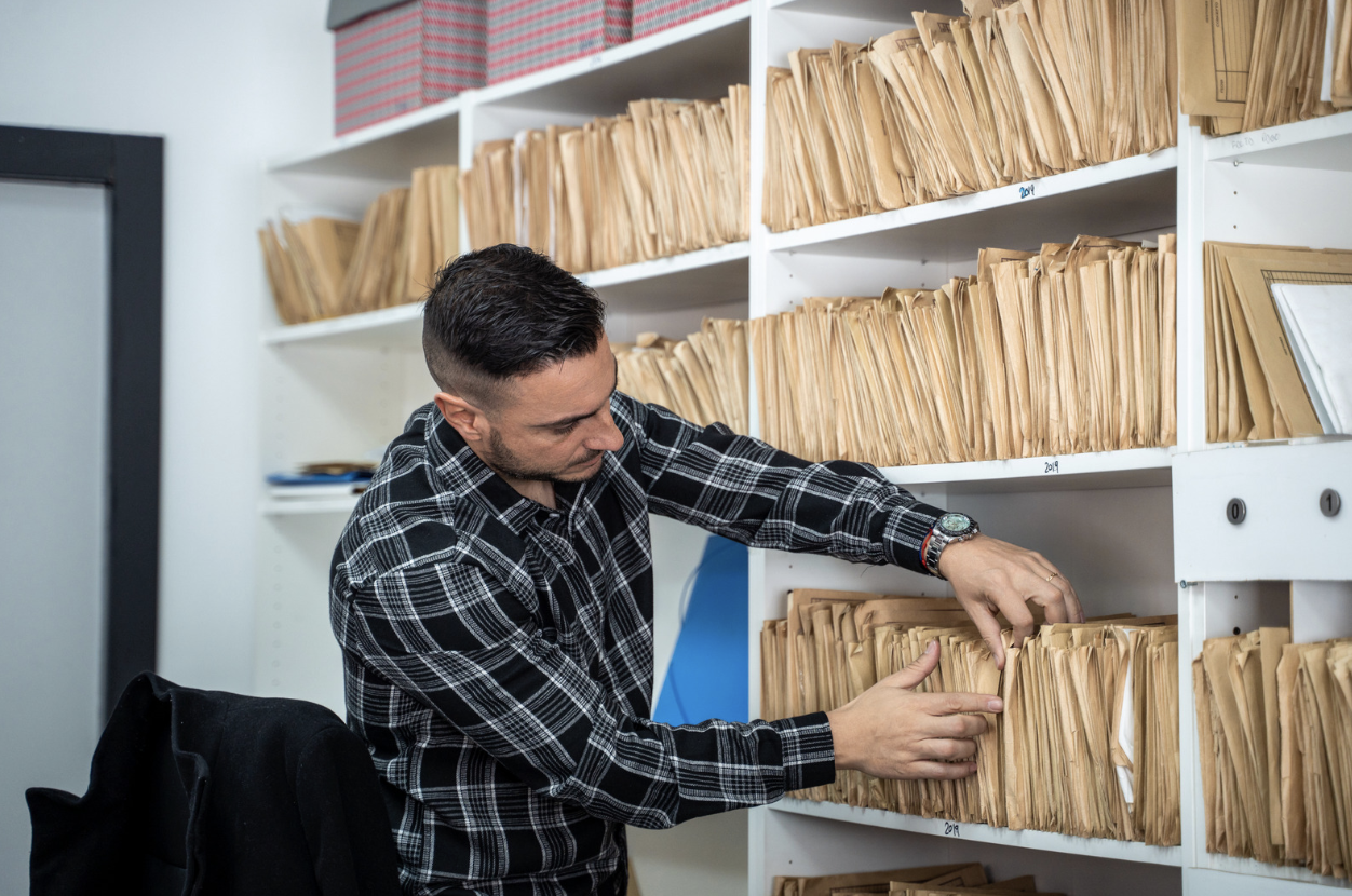 a man searching through files in a shelf 