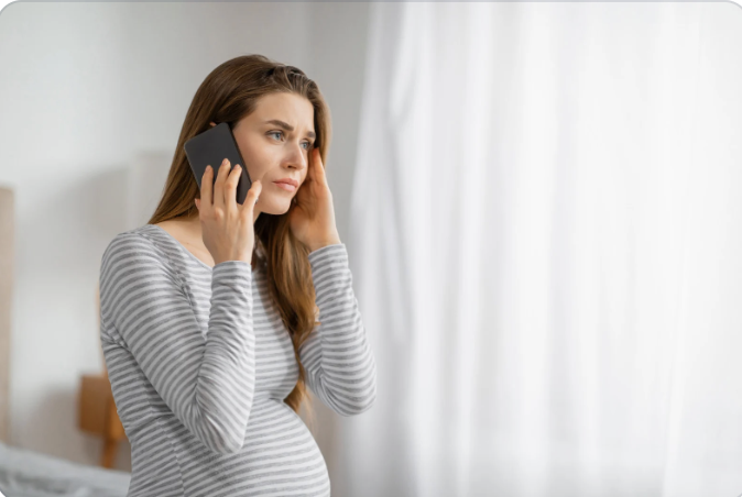 a pregnant woman on a phone call with a focus yet concerned expression