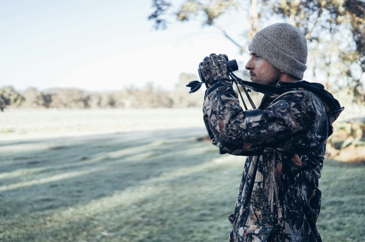 a man in hunting camouflage using binoculars
