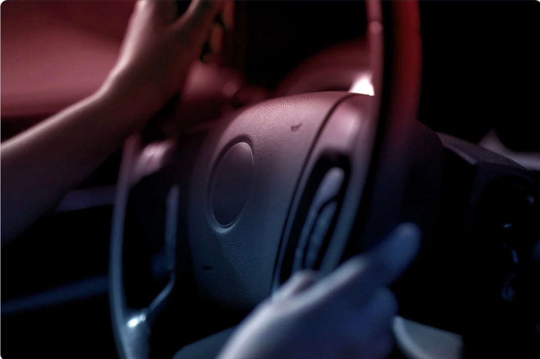 a person holding a steering wheel driving at night