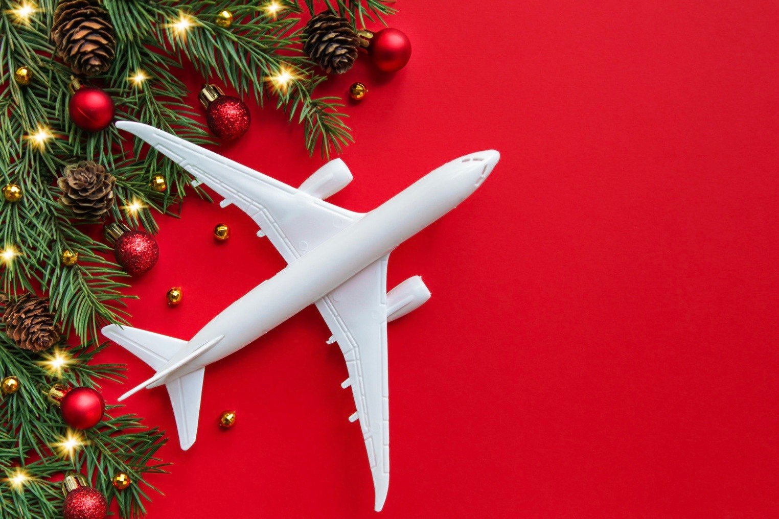 a white airplane in front of a red back ground with Christmas decor