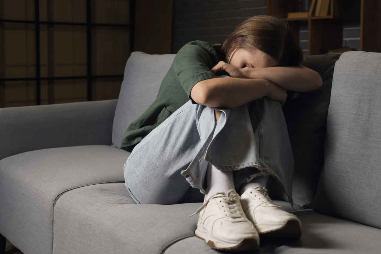 a young woman curled up, cowarding on the couch