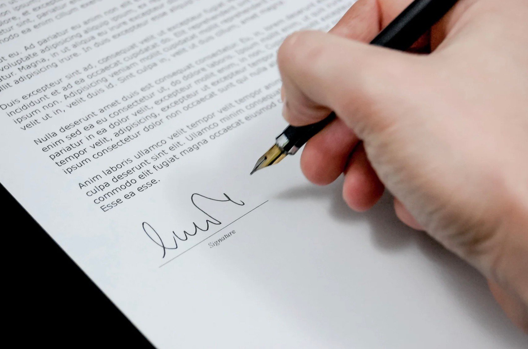 the hand of a person signing a contract