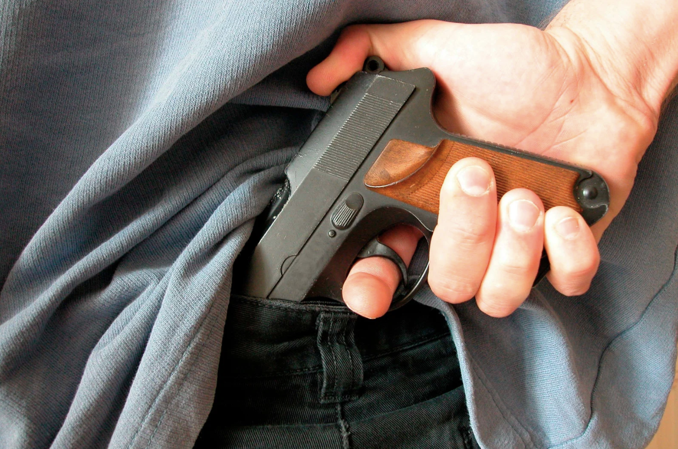 a man puling a gun out from the back side of his pants