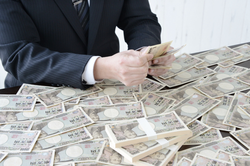a man counting a giant pile of dollar bills on a table