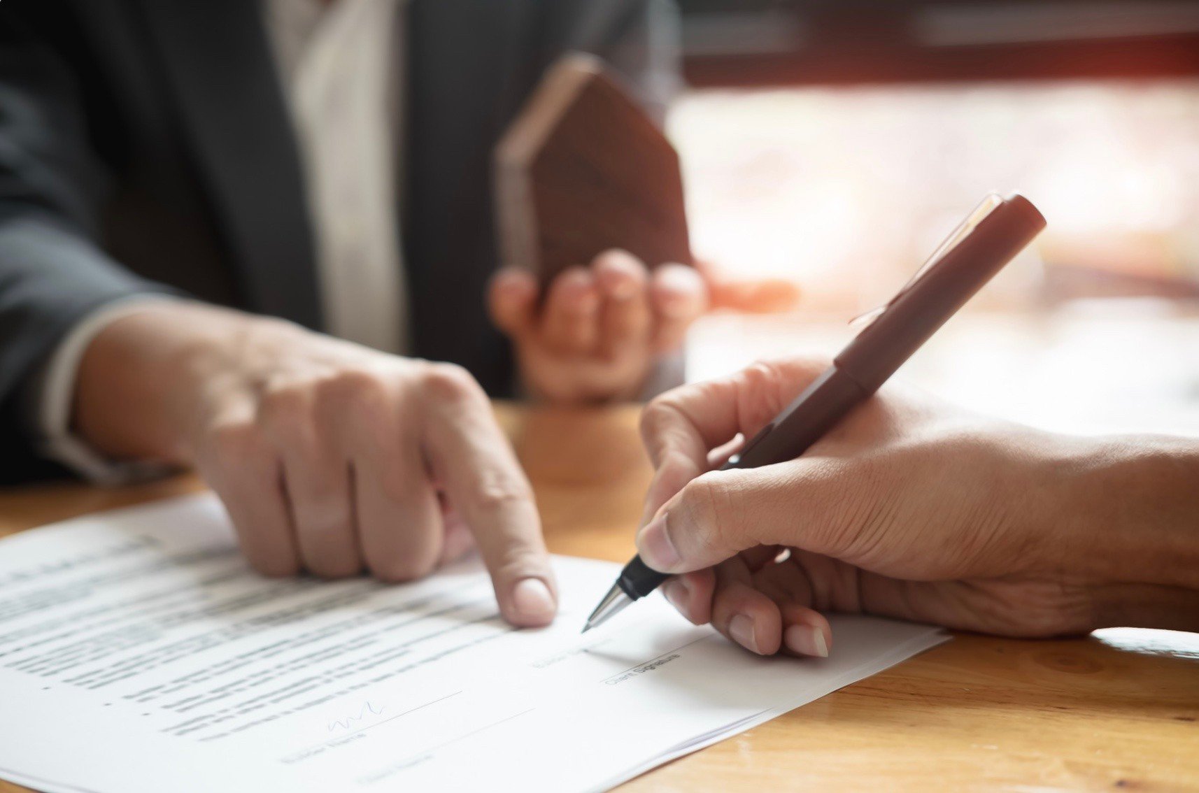 a person signing a contract with a person pointing where to sign