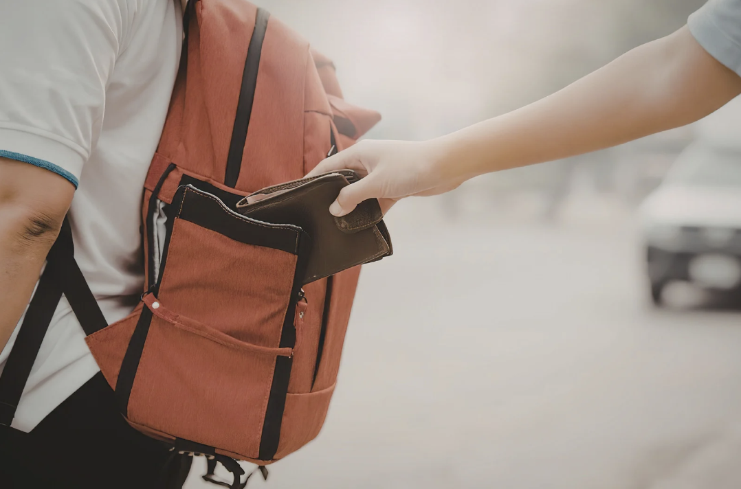 a person stealing a wallet form somebodies backpack