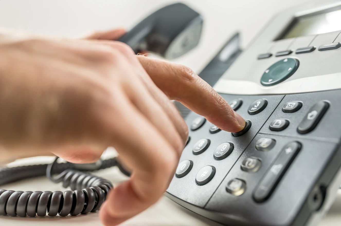 A person dialing on a landline telephone