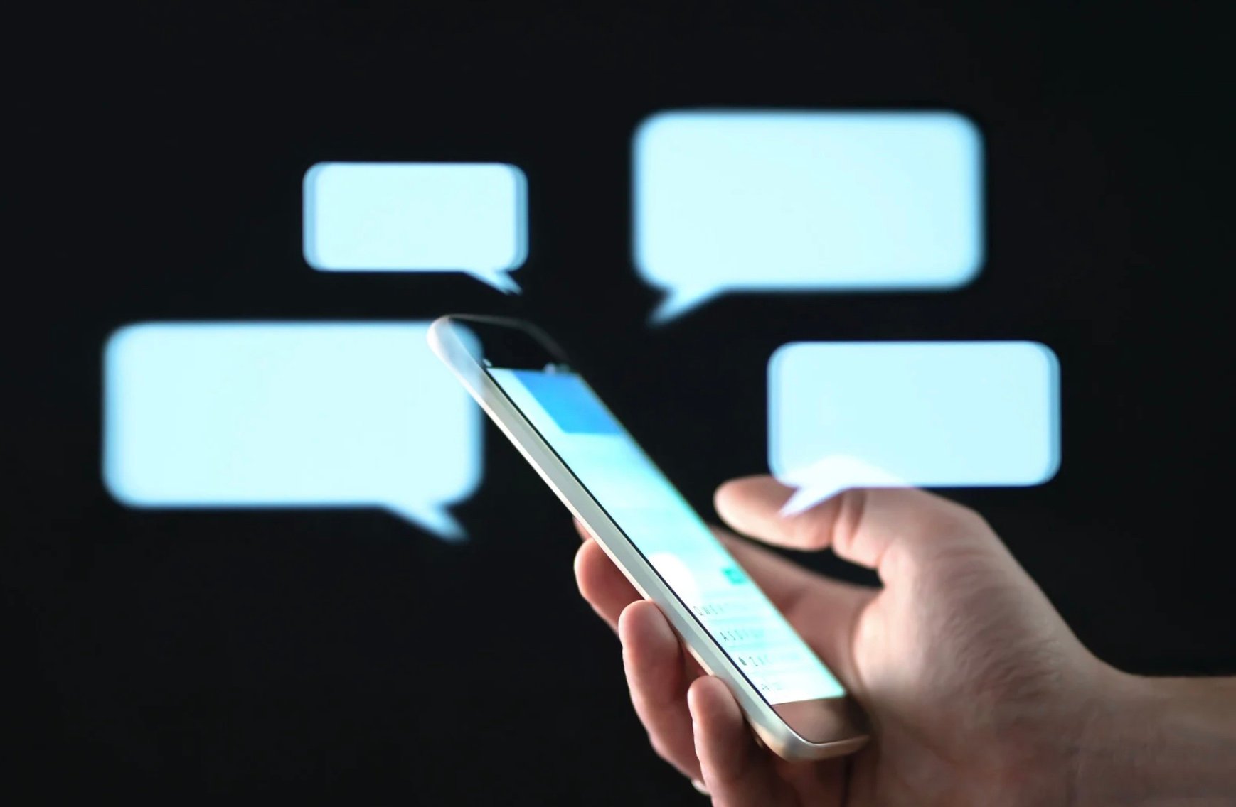  hand holding a cell phone with chat bubbles behind it 