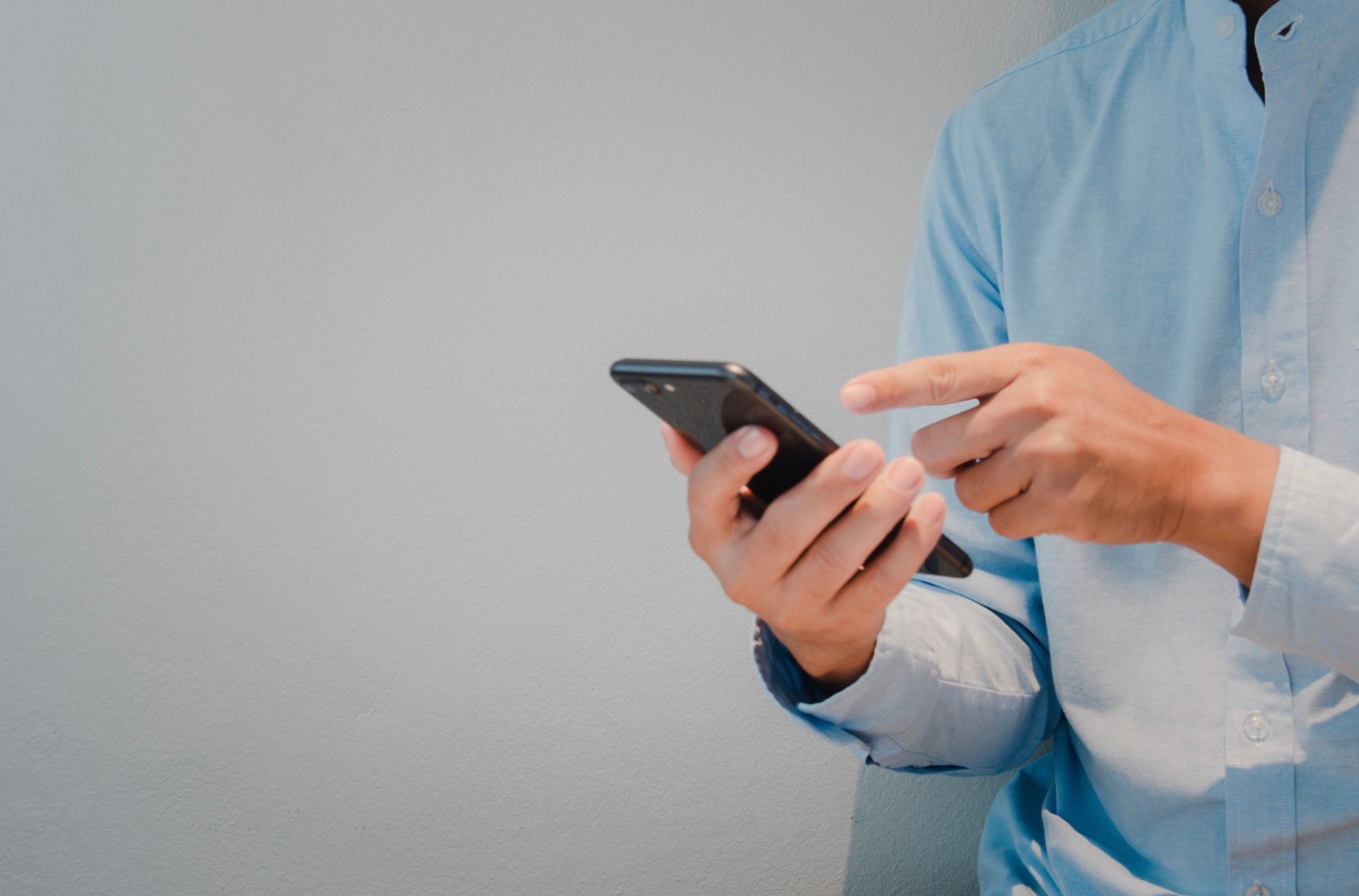 a man holding his cellphone looking for a contact to call