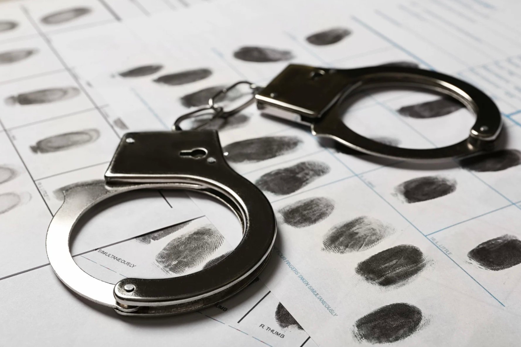 a pair of handcuffs onto of a fingerprint screening document 