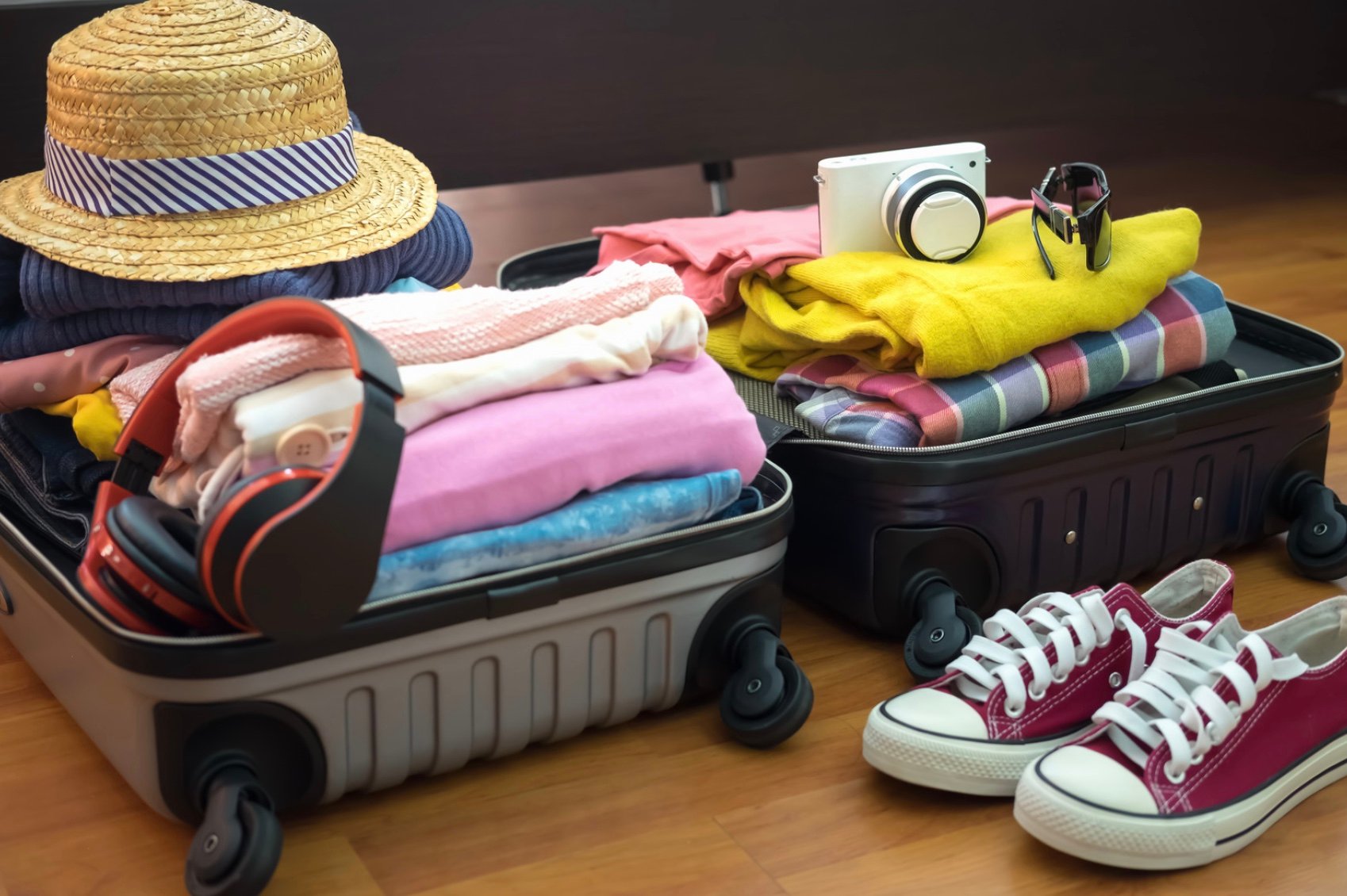 two opened suitcases with clothes hanging out 