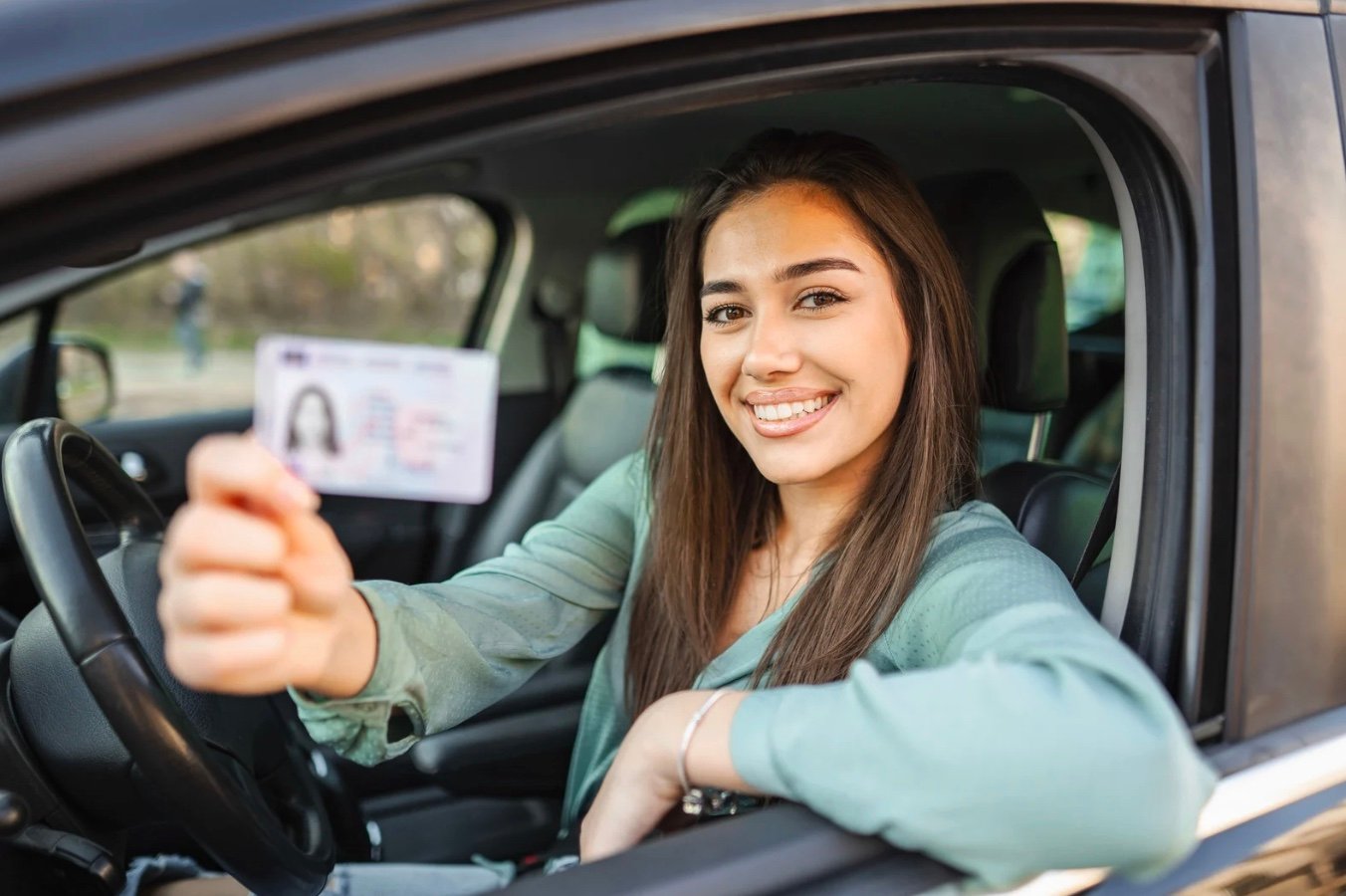 a woman in a car holding up her drivers license