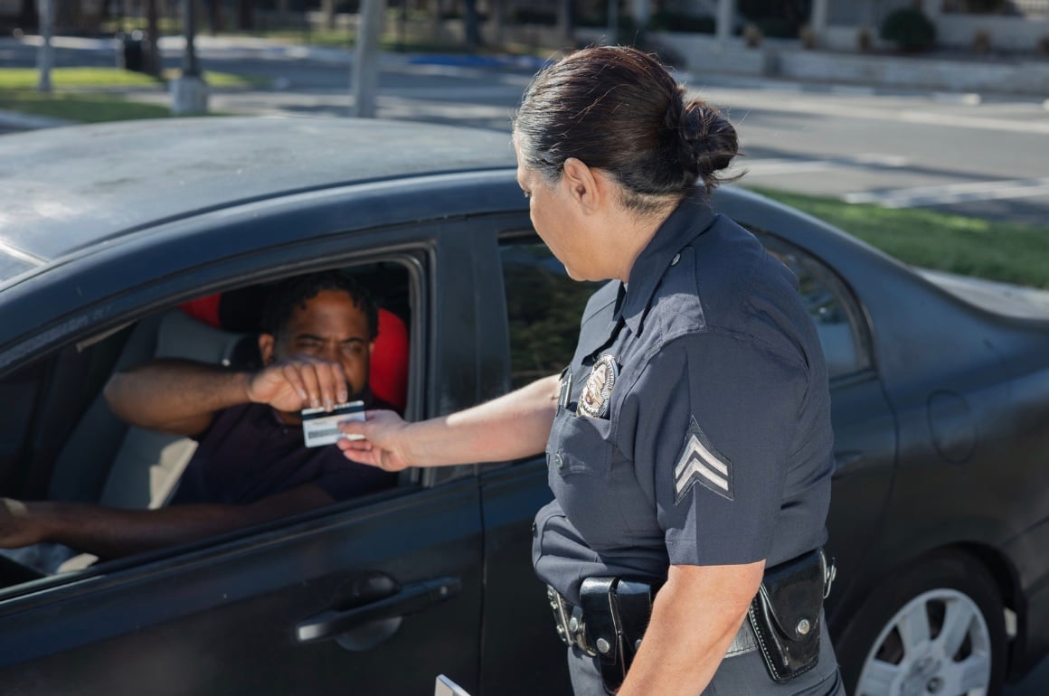a man handing his drivers license to an officer who pulled him over