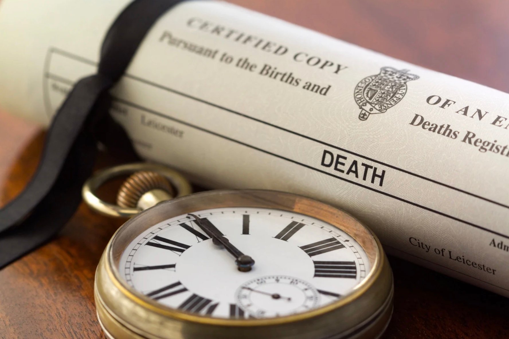 a death certificate next to a pocket watch 