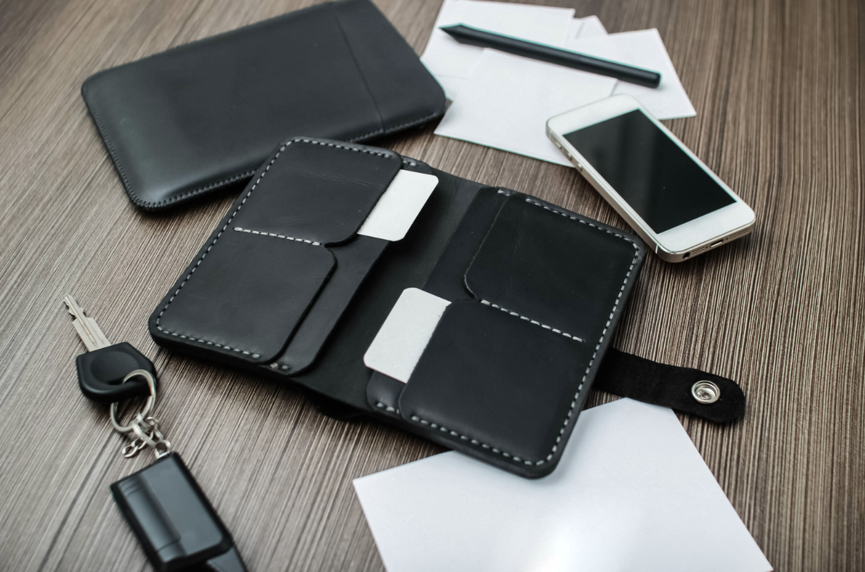 a pile of personal belongings (phone, wallet, keys, etc) on a table