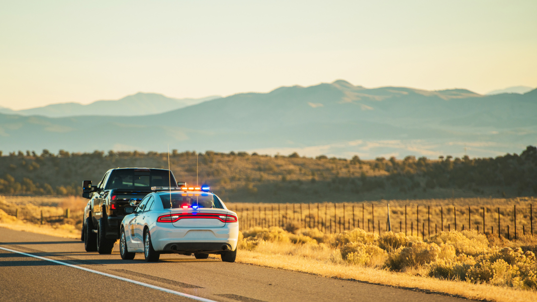 Black truck pulled over by a police car