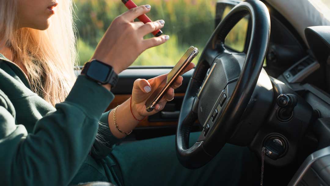 young woman smoking and texting then driving